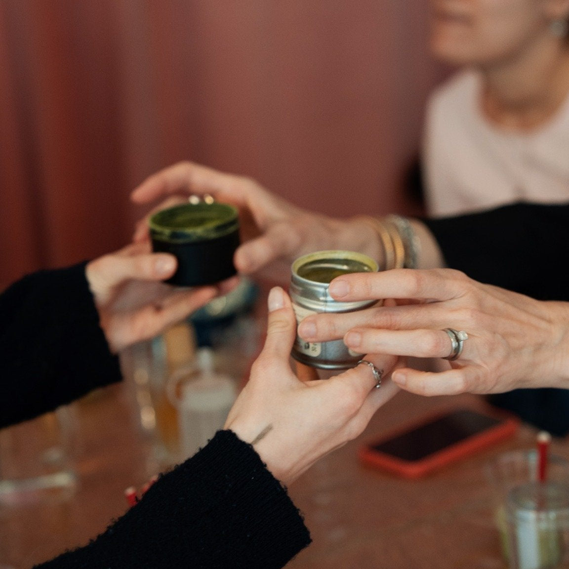 Workshop-Teilnehmer reichen sich Matcha-Dosen rüber