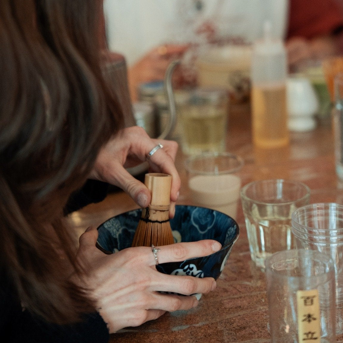 Workshop-Teilnehmer schlägt den Matcha in der Schale mit Matchabesen auf