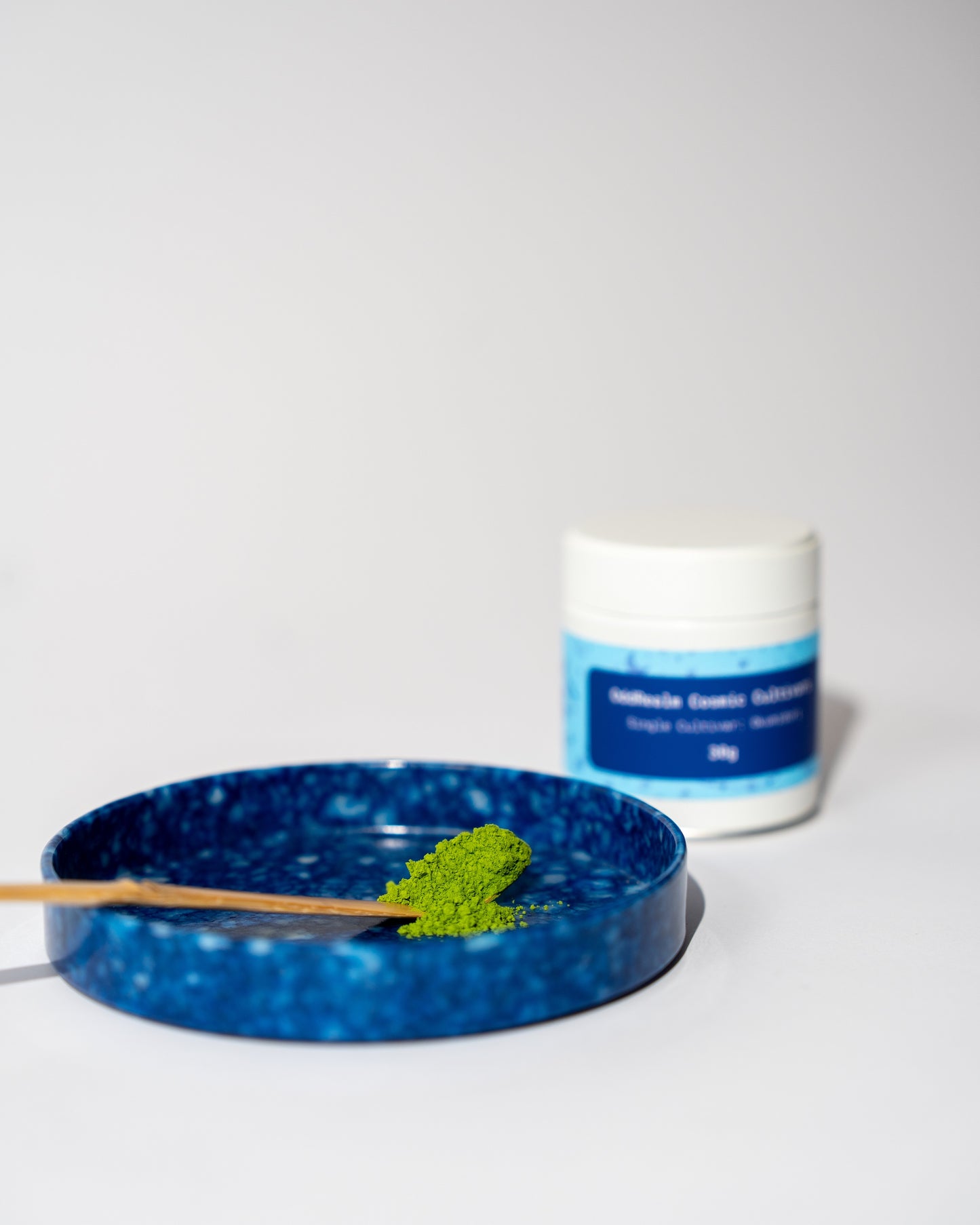 OddRealm Cosmic Cultivar Okumidori Matcha Pulver Nahaufnahme mit Dose im Hintergrund